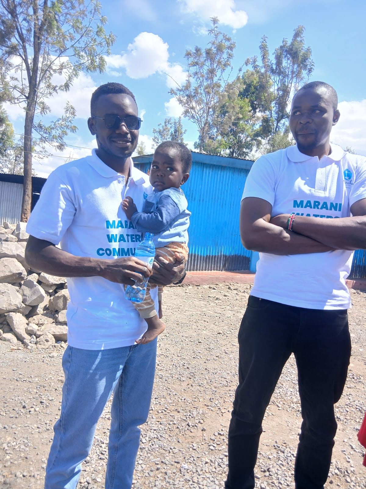 Two Marani Waters volunteers, one holding a young child, at the center