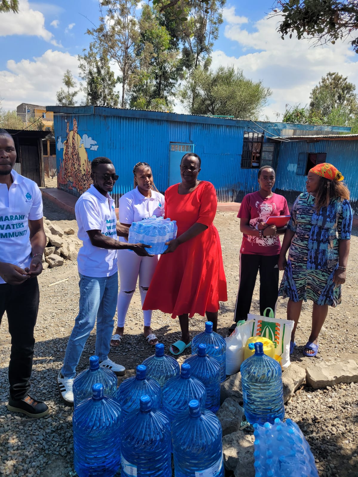 Marani Waters team handing over bottled water beside the donated supplies